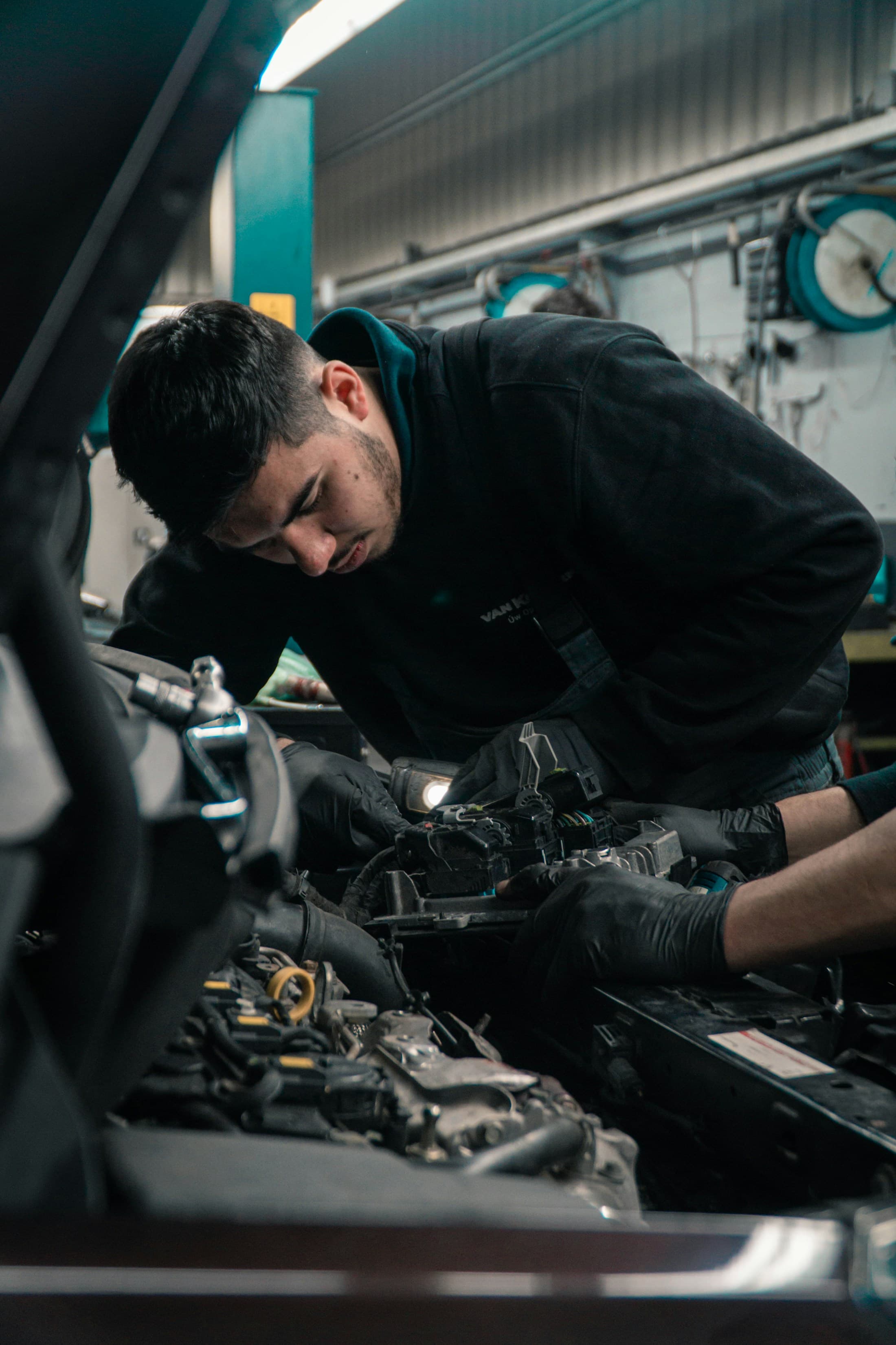 A mechanic in workwear servicing a vehicle in a workshop